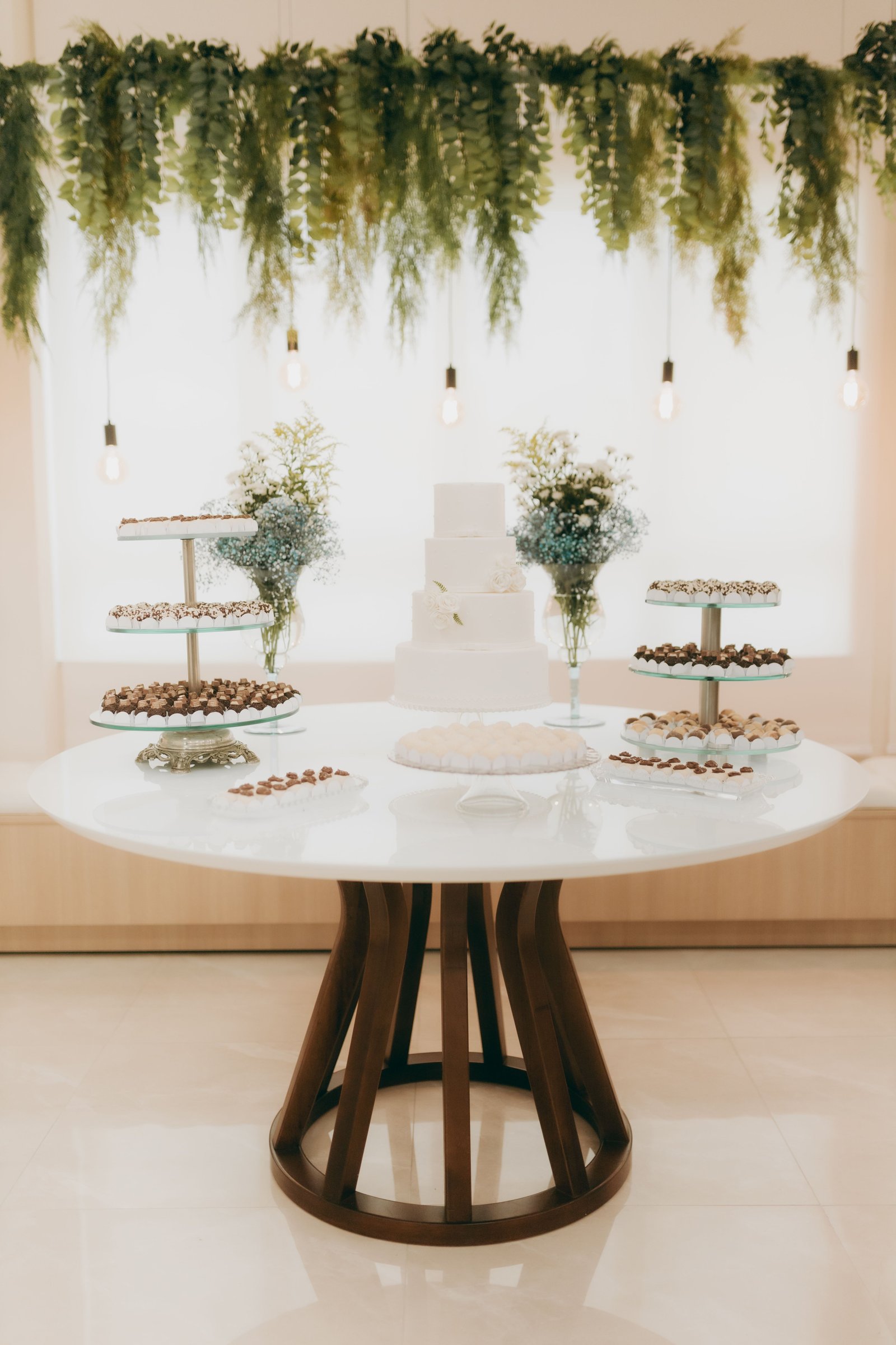 Elegant wedding dessert table with tiered white cake and chocolates